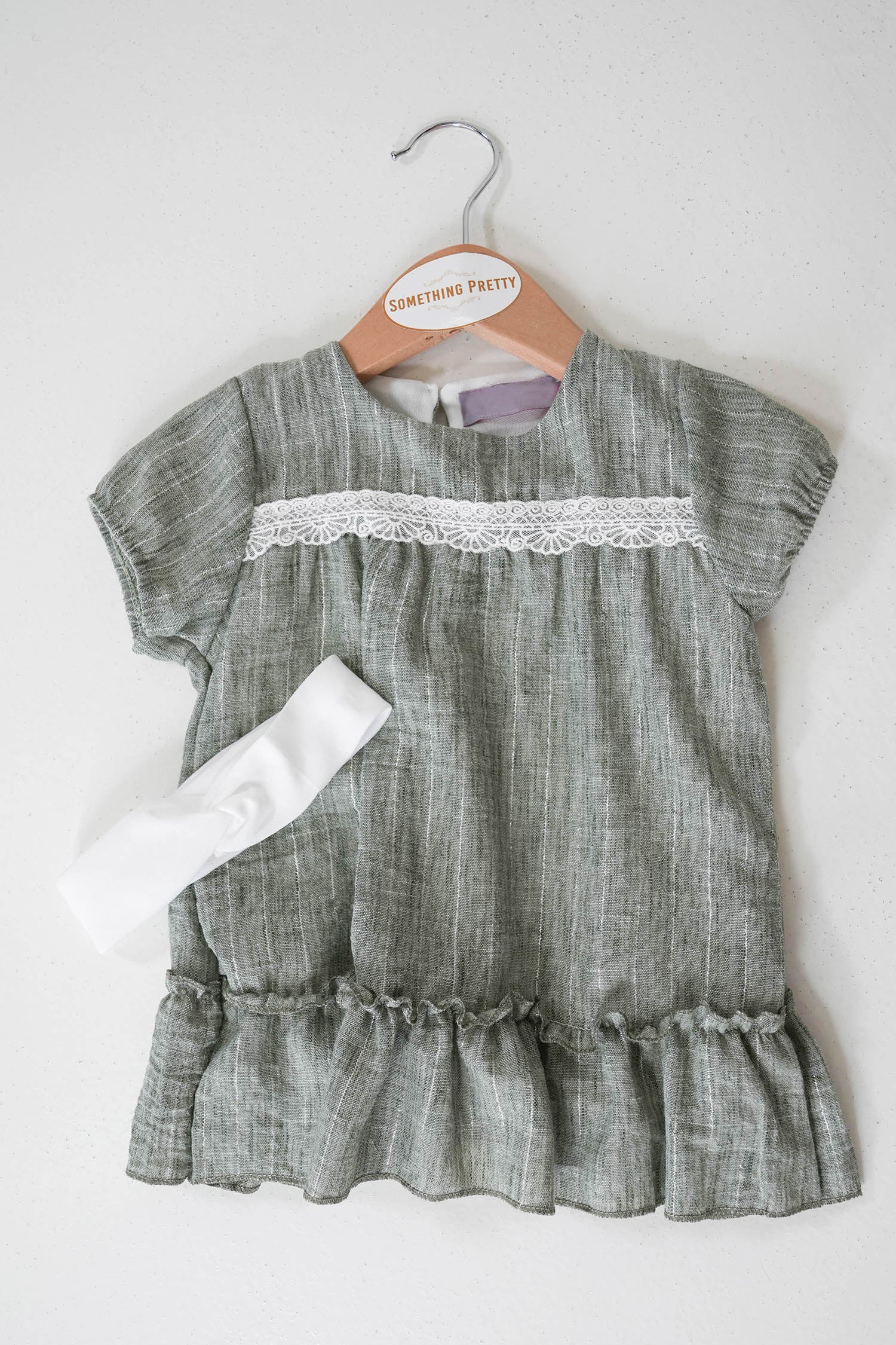Green dress for small child on a hanger with the Something Pretty logo