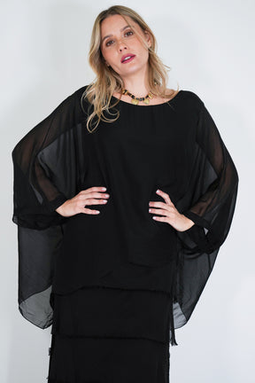 Woman wearing a black outfit with sheer sleeves against a white background