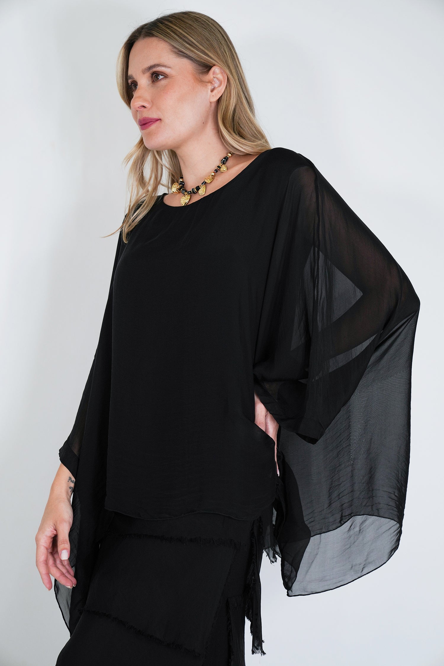 Woman wearing a black outfit with sheer sleeves against a white background
