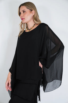 Woman wearing a black outfit with sheer sleeves against a white background