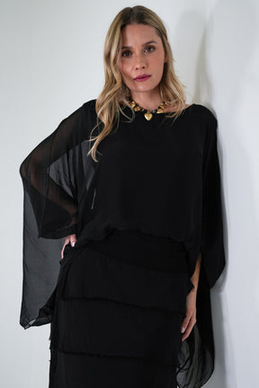 Woman wearing a black layered outfit against a white background