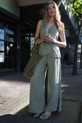 Woman in a green outfit holding a drink on a city street