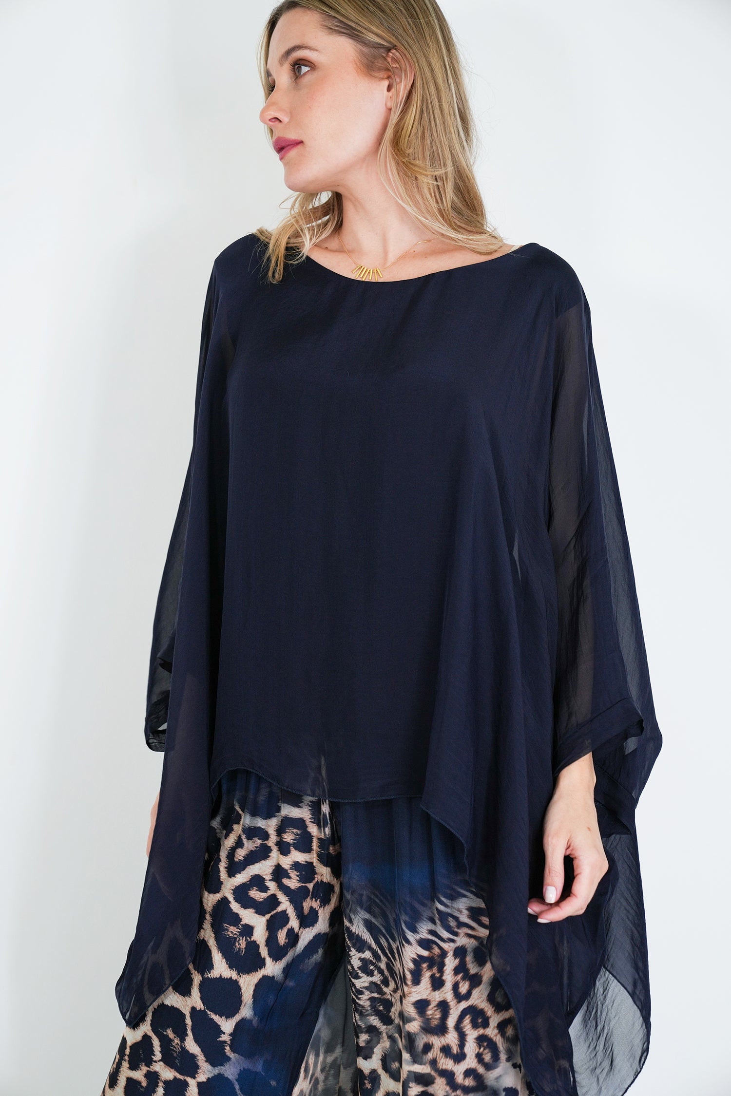 Woman wearing a navy blue top and leopard print pants against a white background