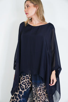 Woman wearing a navy blue top and leopard print pants against a white background