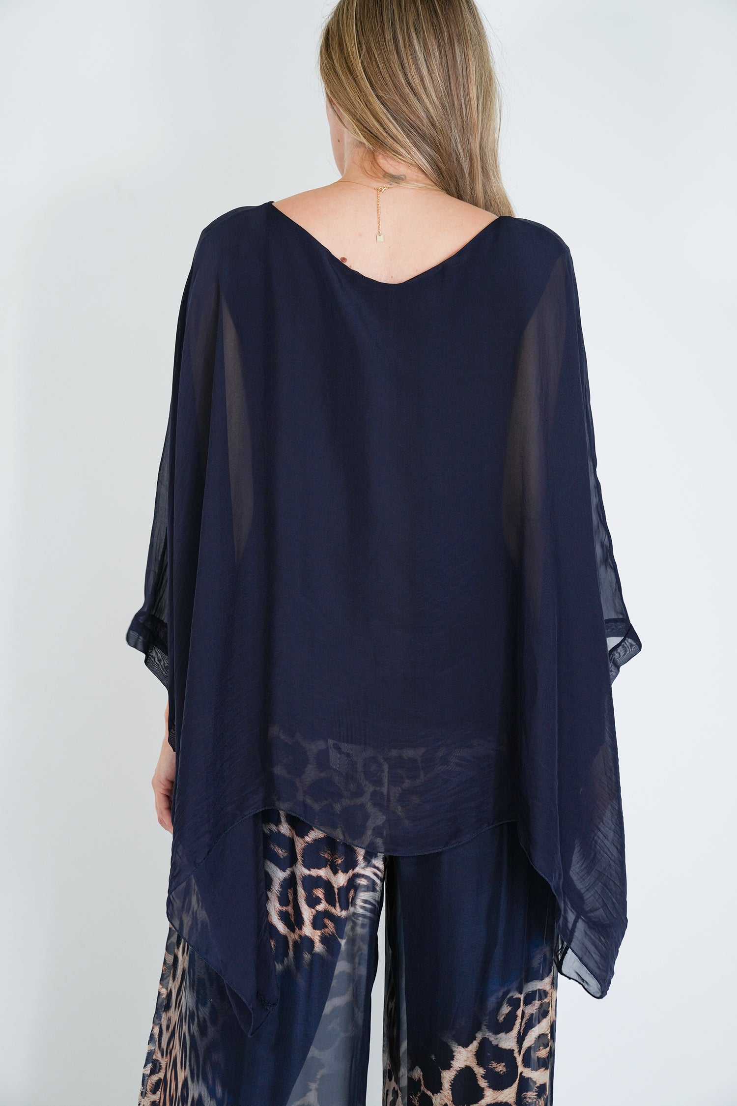 Navy blue sheer top worn by a person on a white background