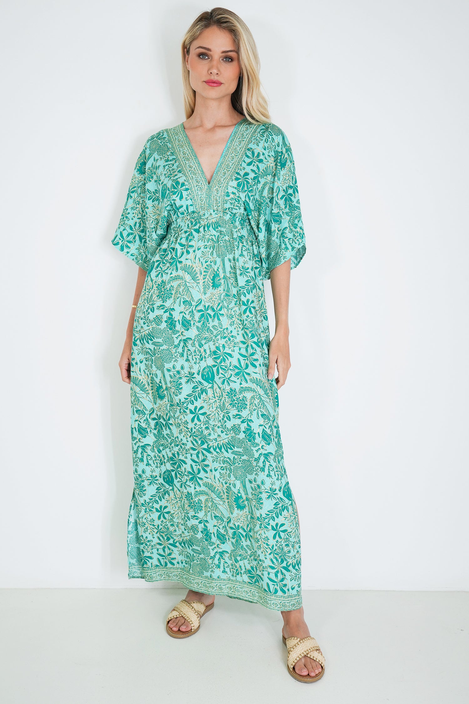 Woman wearing a green floral dress against a white background