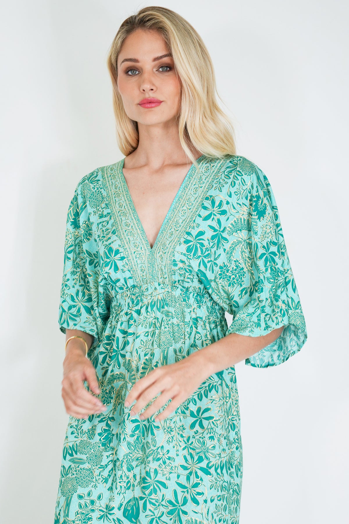 Woman wearing a green floral dress against a white background