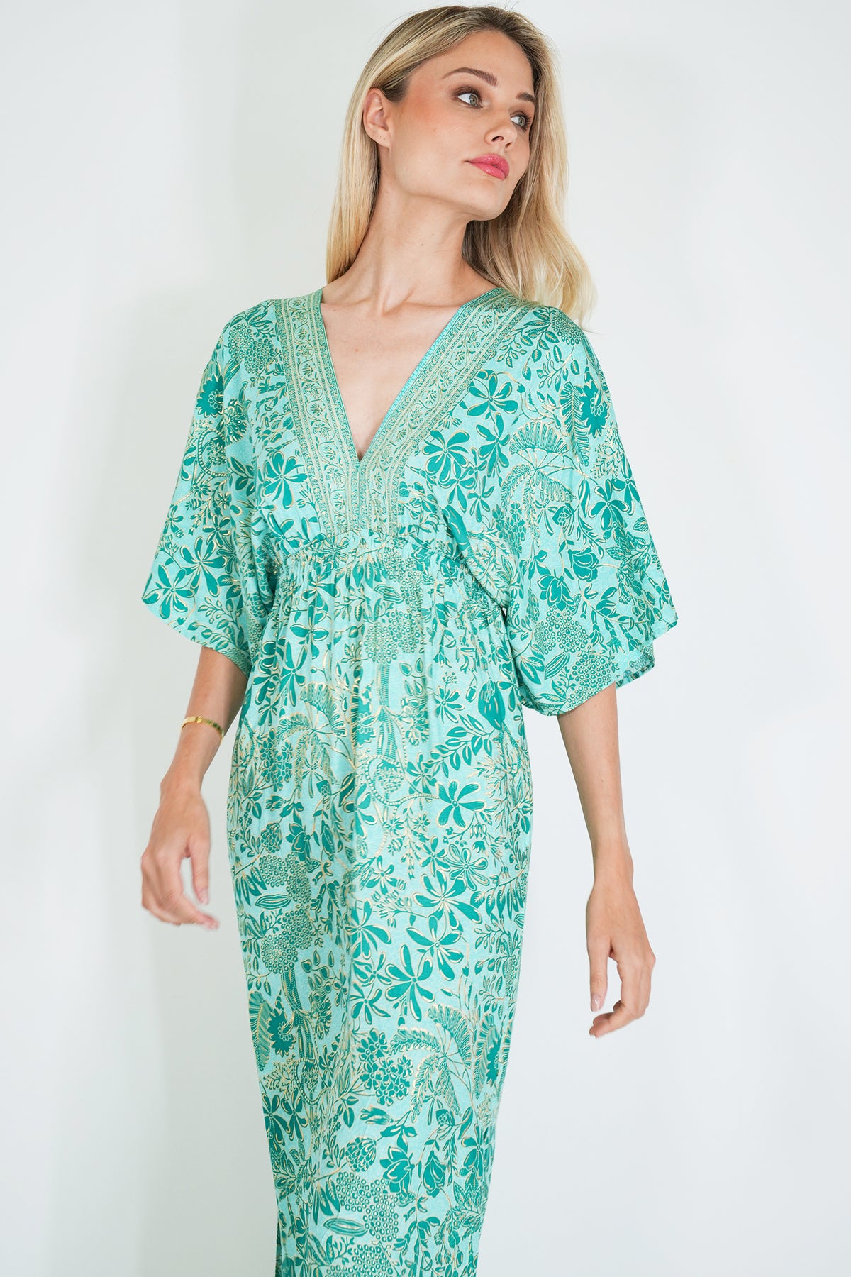 Woman wearing a green floral dress against a white background