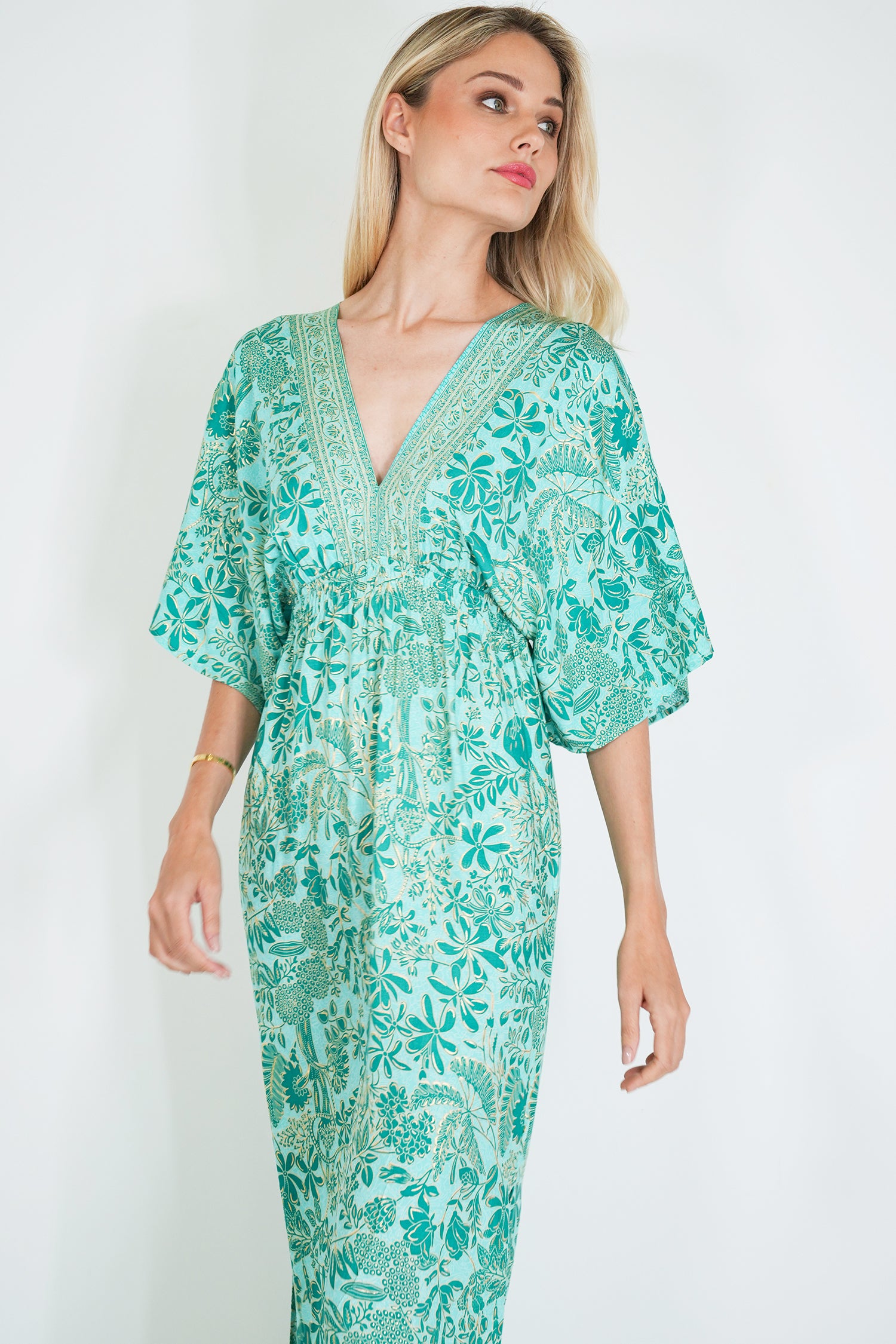 Woman wearing a green floral dress against a white background