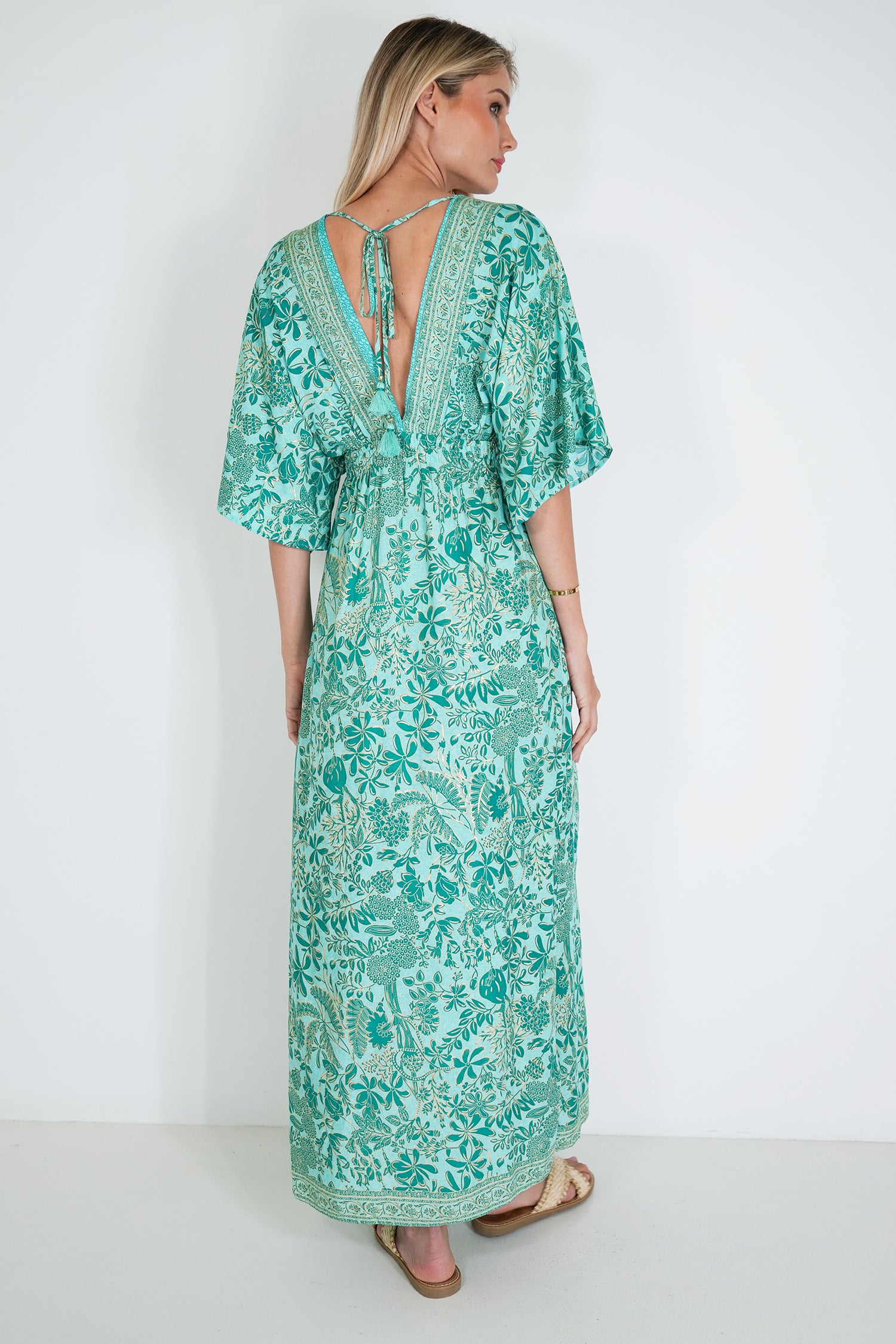 Woman wearing a green floral dress against a white background