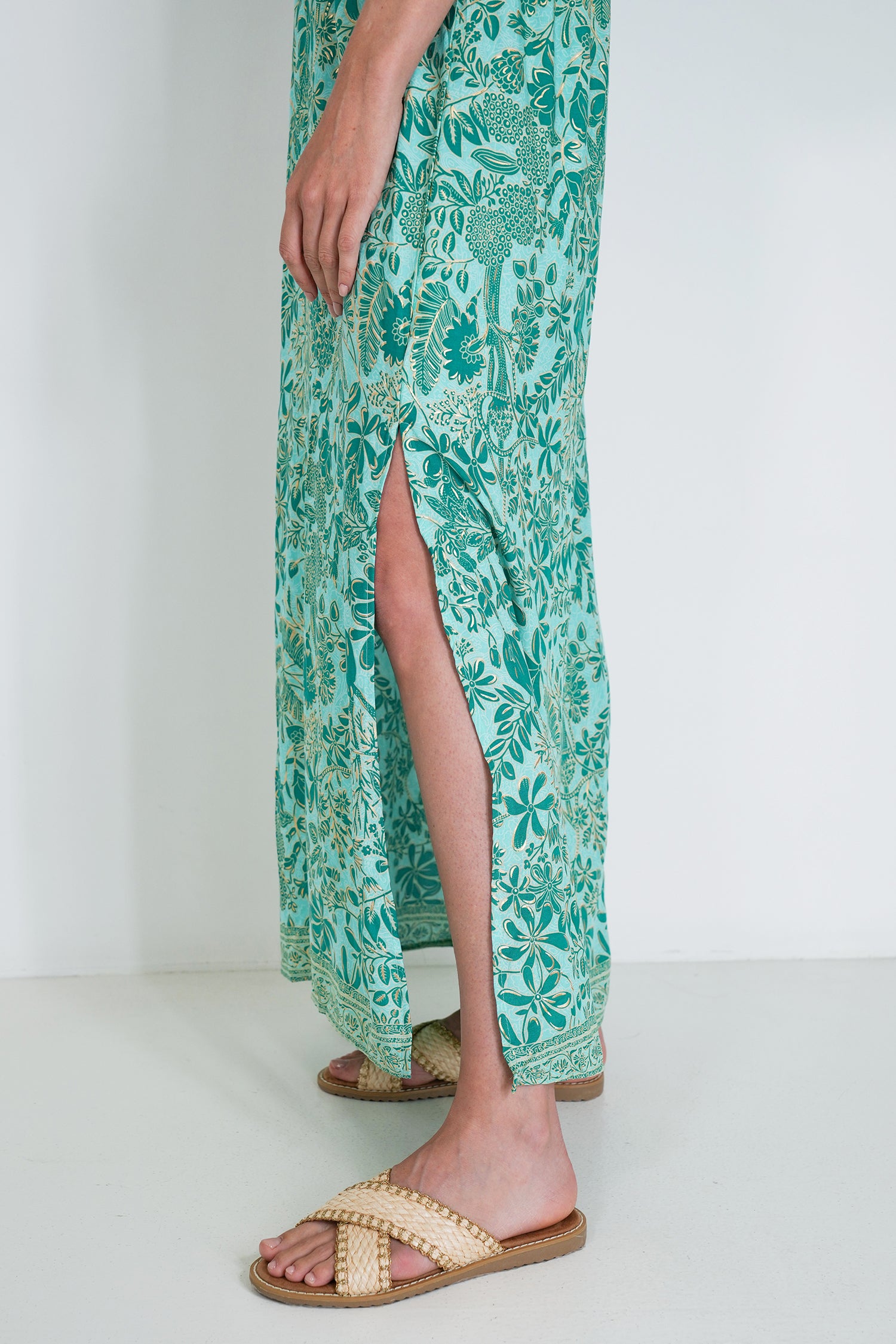Person wearing a green floral dress with a white background
