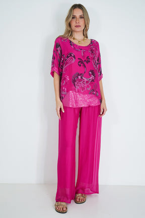 Woman wearing a bright pink outfit with floral patterns on a white background