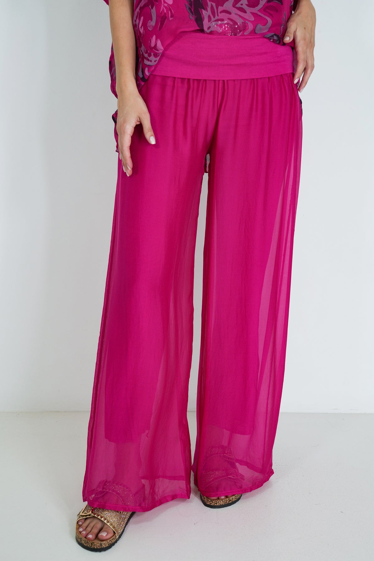 Person wearing bright pink wide-leg pants on a white background