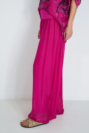 Person wearing a bright pink dress with a white background