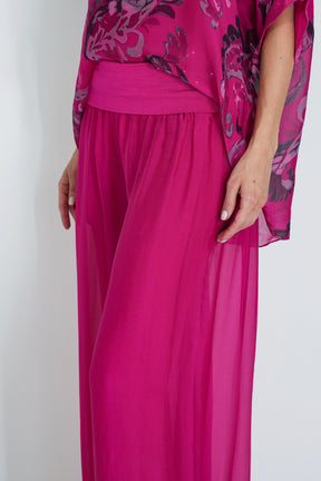 Person wearing a bright pink outfit with floral patterns on a white background