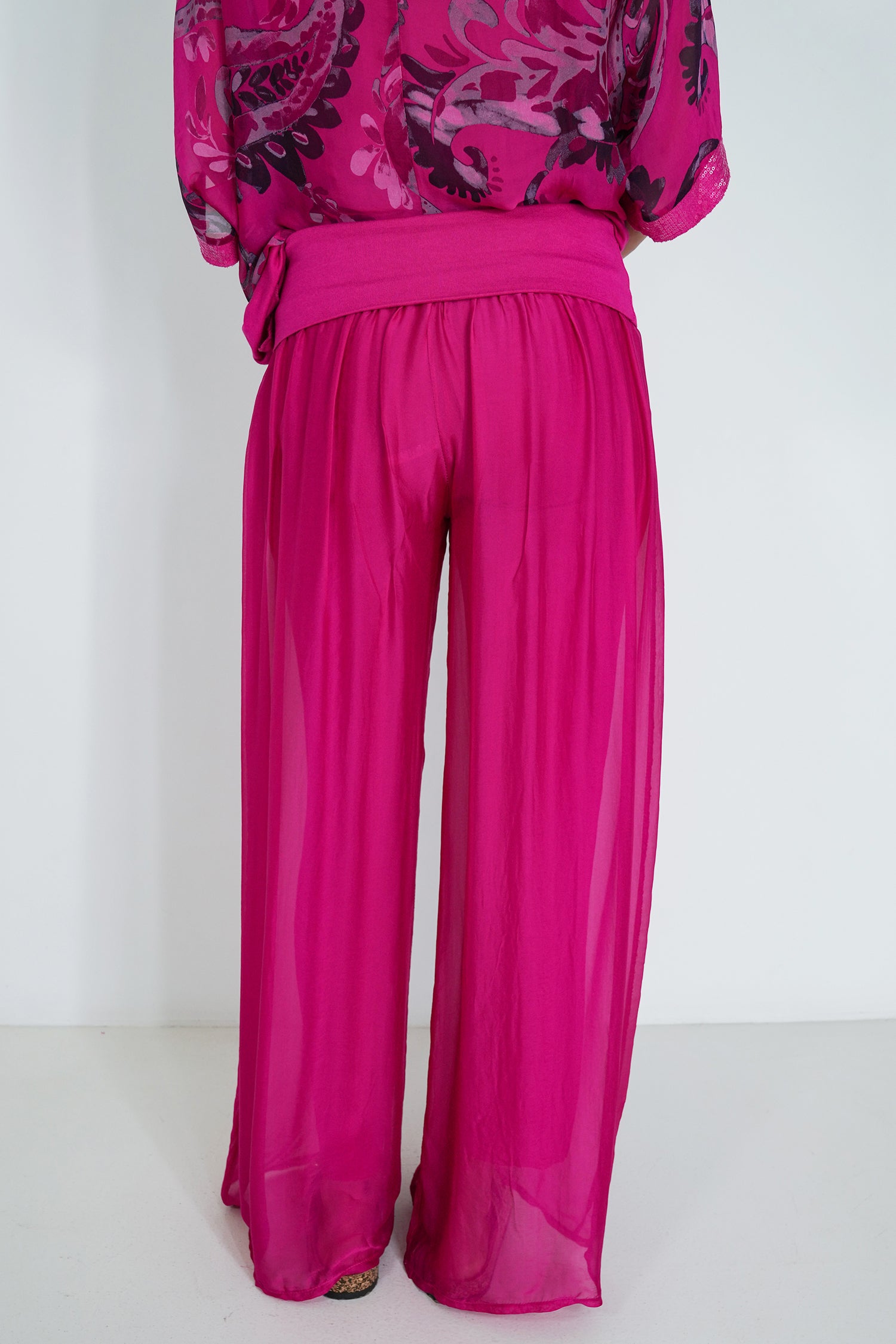 Fuchsia outfit with a patterned top and wide-leg pants on a white background