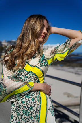 Woman wearing a patterned dress with yellow accents against a blue sky.