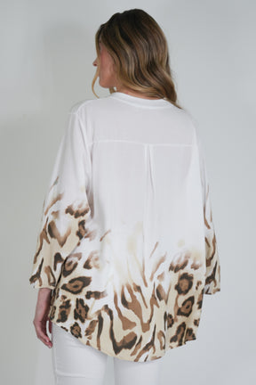 Woman wearing a white blouse with a leopard print pattern on a plain background
