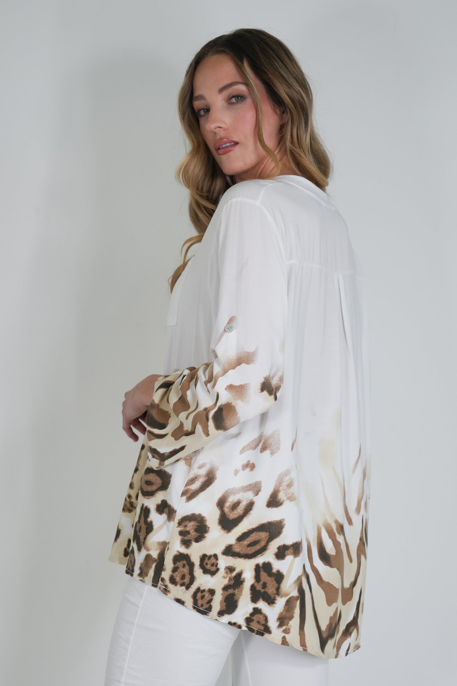 Woman wearing a white kimono-style garment with a leopard print design on a plain background