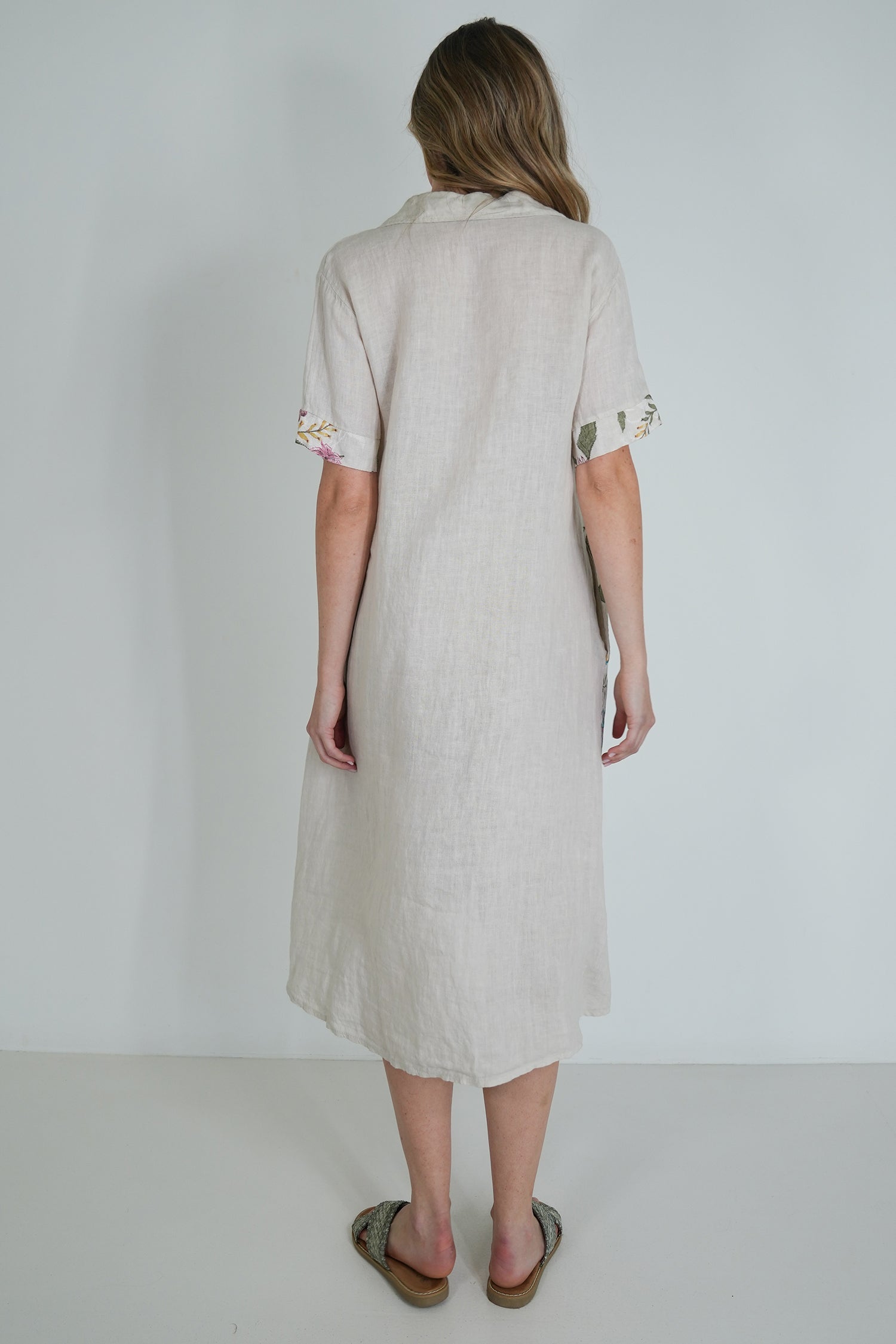 Woman wearing a light-colored dress with lace details on a plain background
