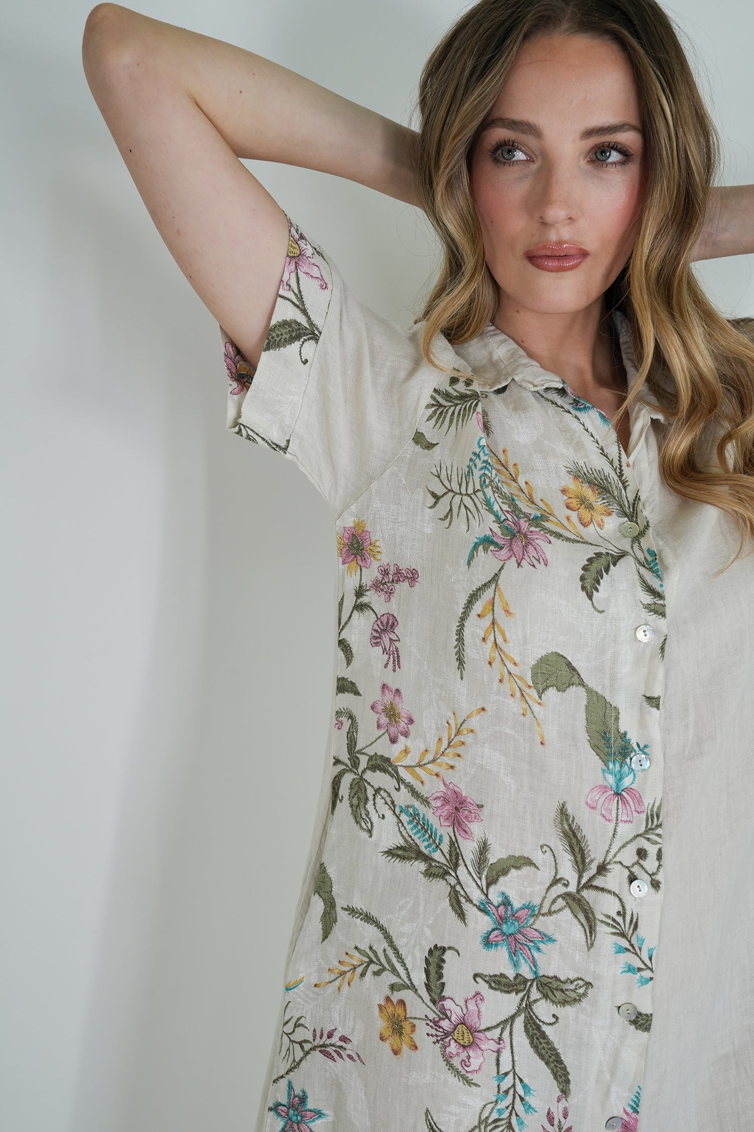 Woman wearing a floral embroidered shirt against a plain background