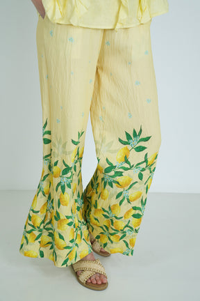 Yellow outfit with lemon print pants on a plain background