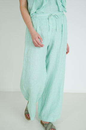 Person wearing light green pants on a white background