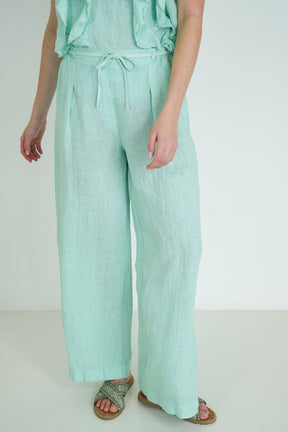 Person wearing light green pants on a plain background