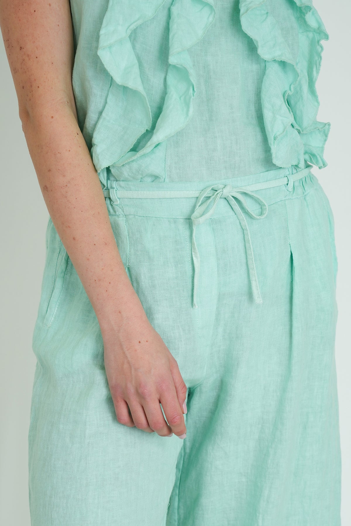 Mint green ruffled top and pants set on a plain background