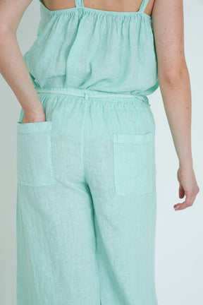 Person wearing a light green jumpsuit on a plain background