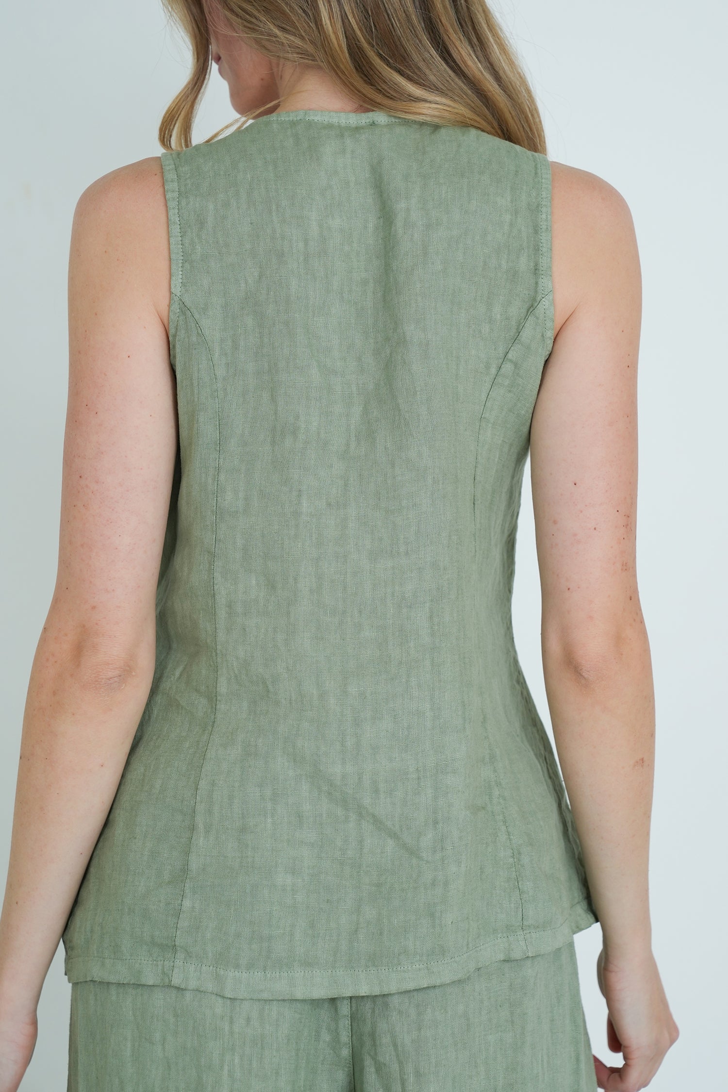 Green sleeveless top worn by a person on a plain background