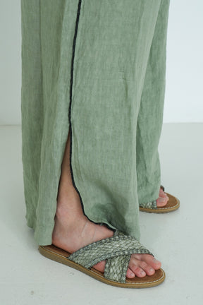 Person wearing green pants and sandals on a white background