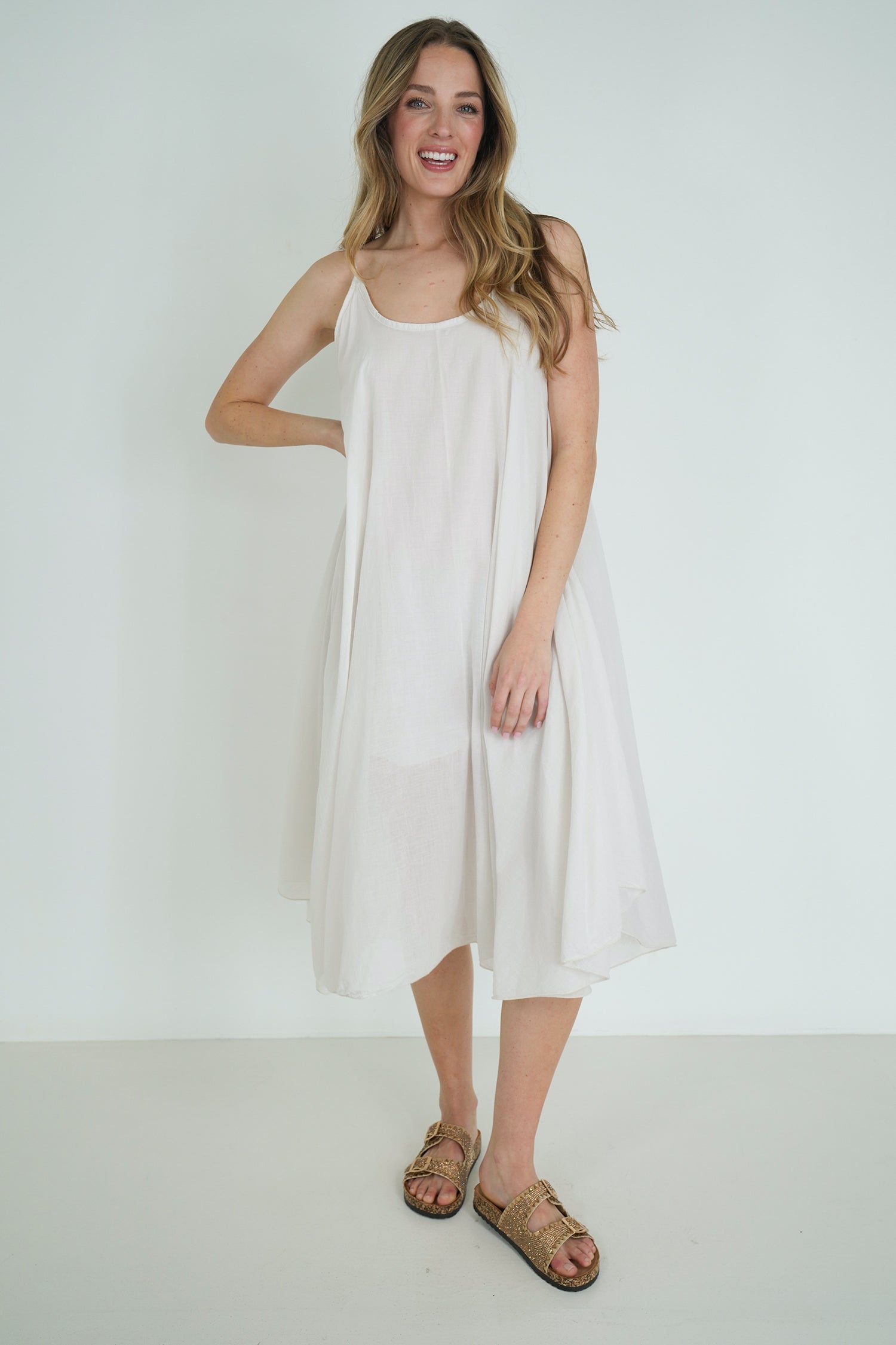 Woman wearing a white dress standing against a plain background
