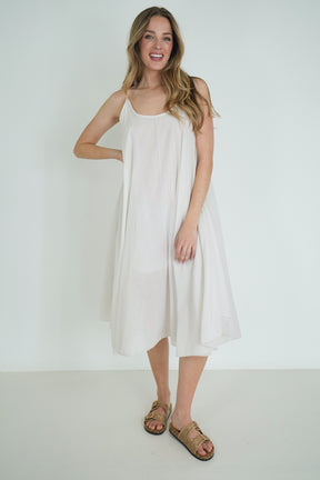 Woman wearing a white dress standing against a plain background
