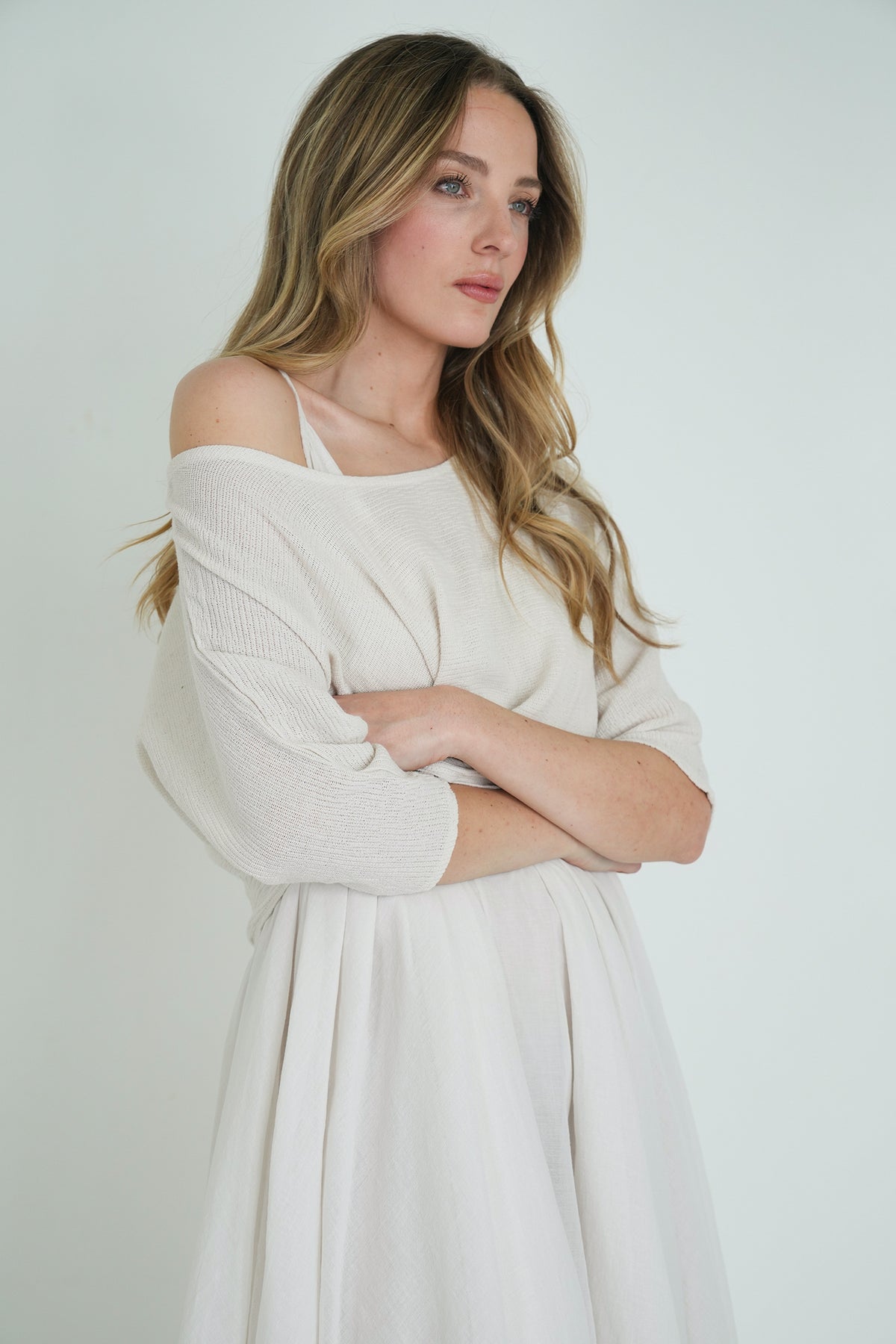 Woman wearing a white off-shoulder dress against a plain background