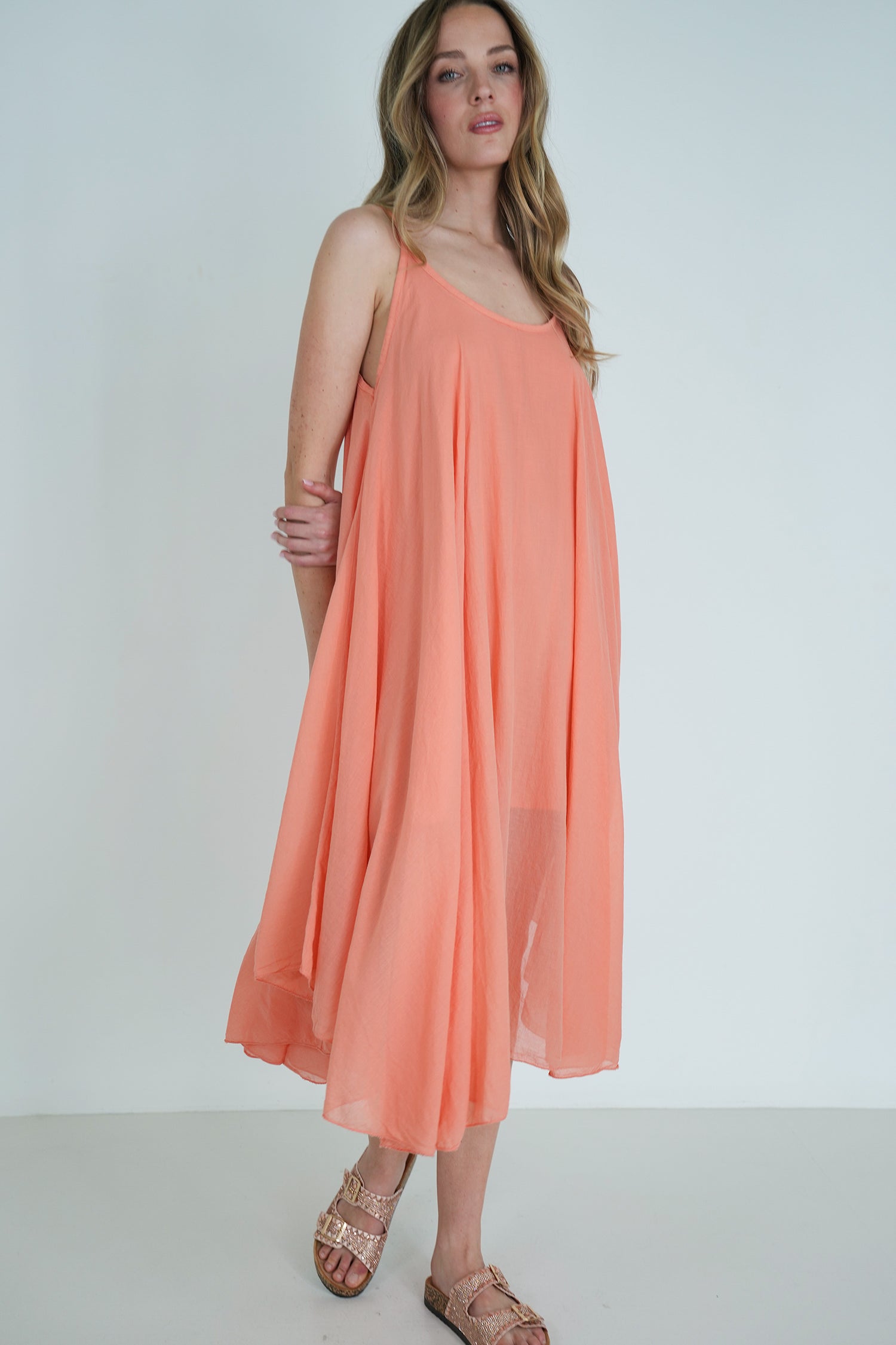 Woman wearing a peach-colored dress against a white background
