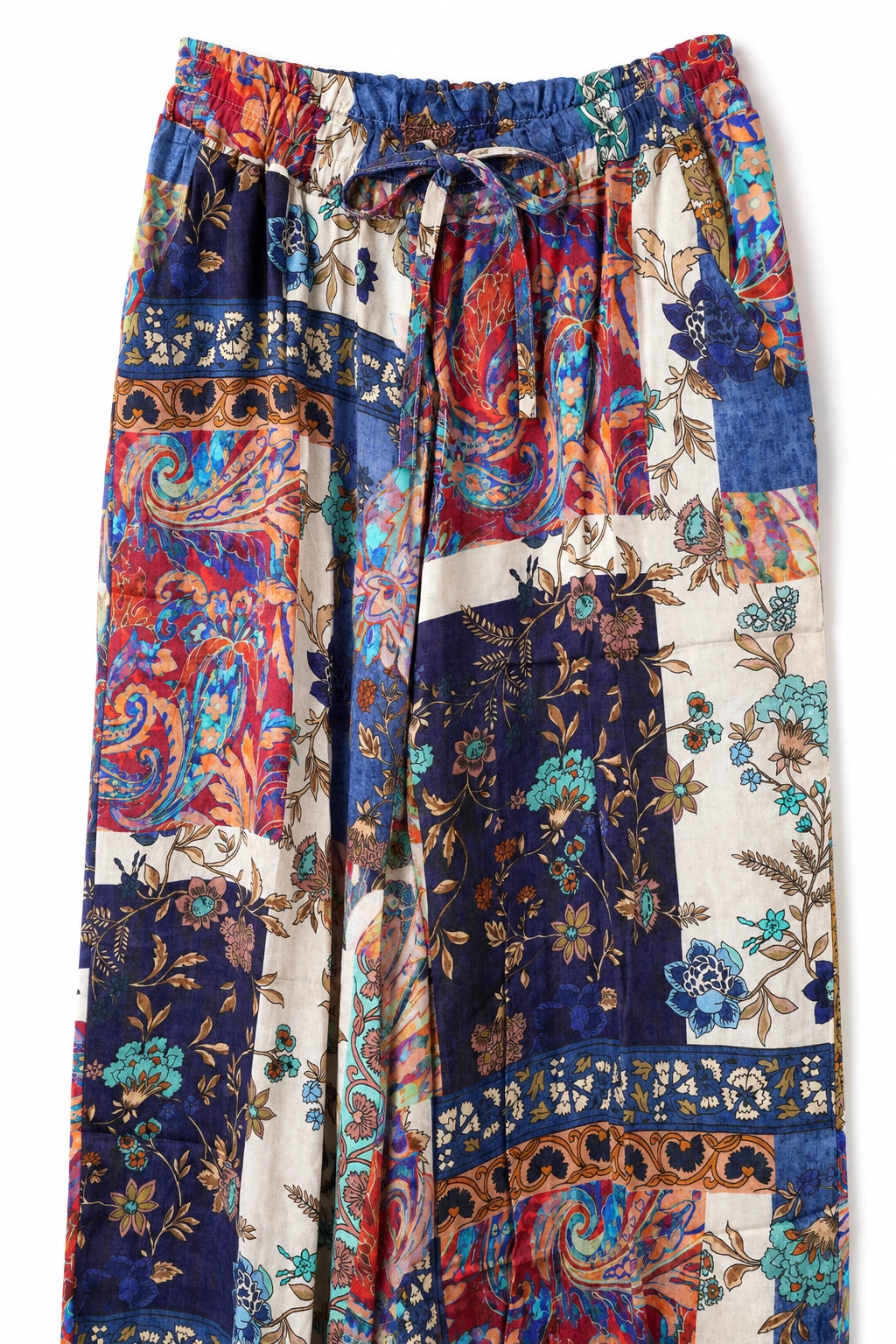 A pair of wide-leg patchwork pants featuring a vibrant mix of paisley, floral, and geometric patterns in blue, red, beige, and brown, with an elastic waistband and drawstring.