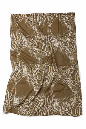 A rectangular fabric item, likely a blanket or throw, featuring an abstract wavy zebra-like pattern in brown and off-white, laid flat on a white background.