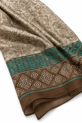 A folded patterned scarf or shawl in beige and brown with a teal geometric border, shown on a plain white background.