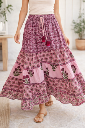 Person wearing a pink floral tiered skirt with a white top indoors.