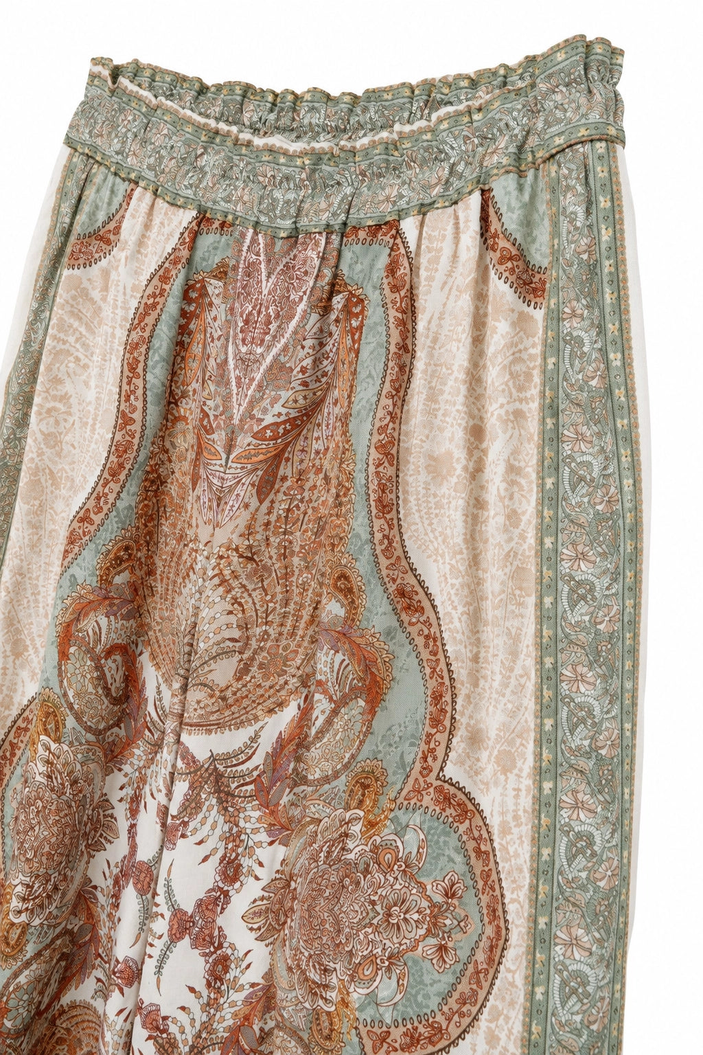 A close-up of a bohemian paisley printed skirt featuring a sage green elastic waistband and a detailed pattern in rust orange, beige, and sage green.