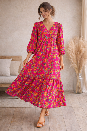 Woman wearing a pink floral dress in a room with a couch and decorative elements.