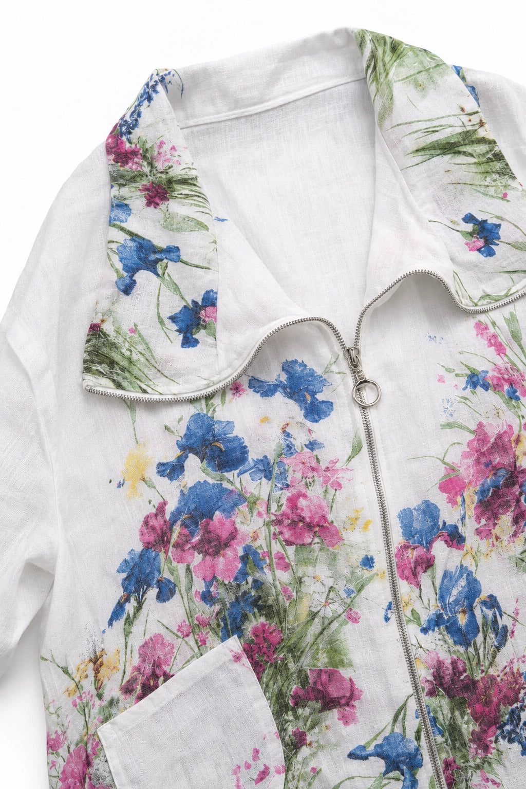 A close-up of a white zip-up jacket featuring a vibrant watercolor floral print with blue, pink, and purple flowers and green leaves.
