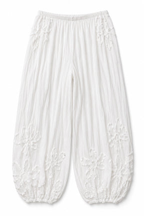 White crinkled cotton pants with embroidered floral patterns and elasticated cuffs, shown flat on a white background.
