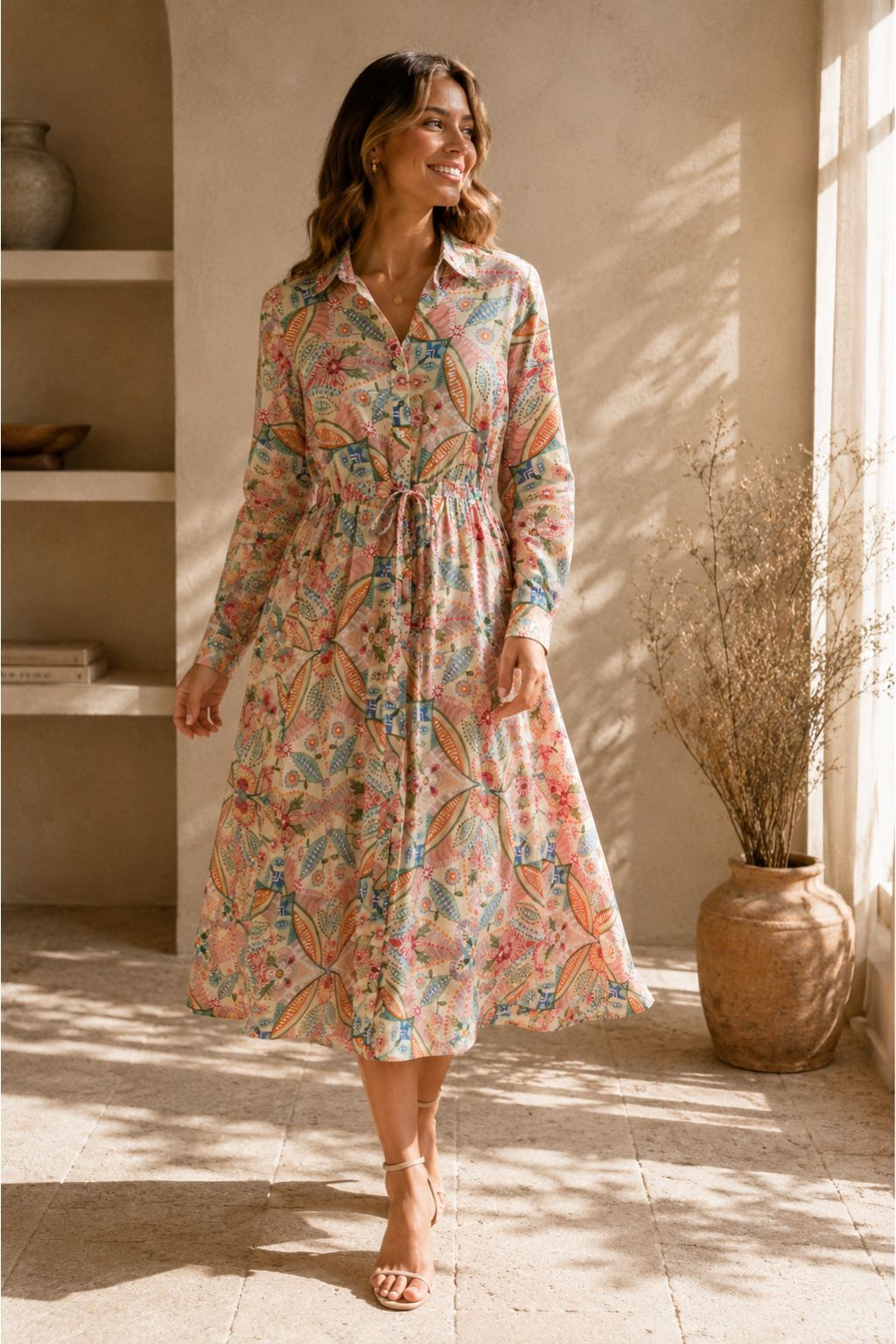 Woman wearing a floral dress in a sunlit room with a vase and plant in the background