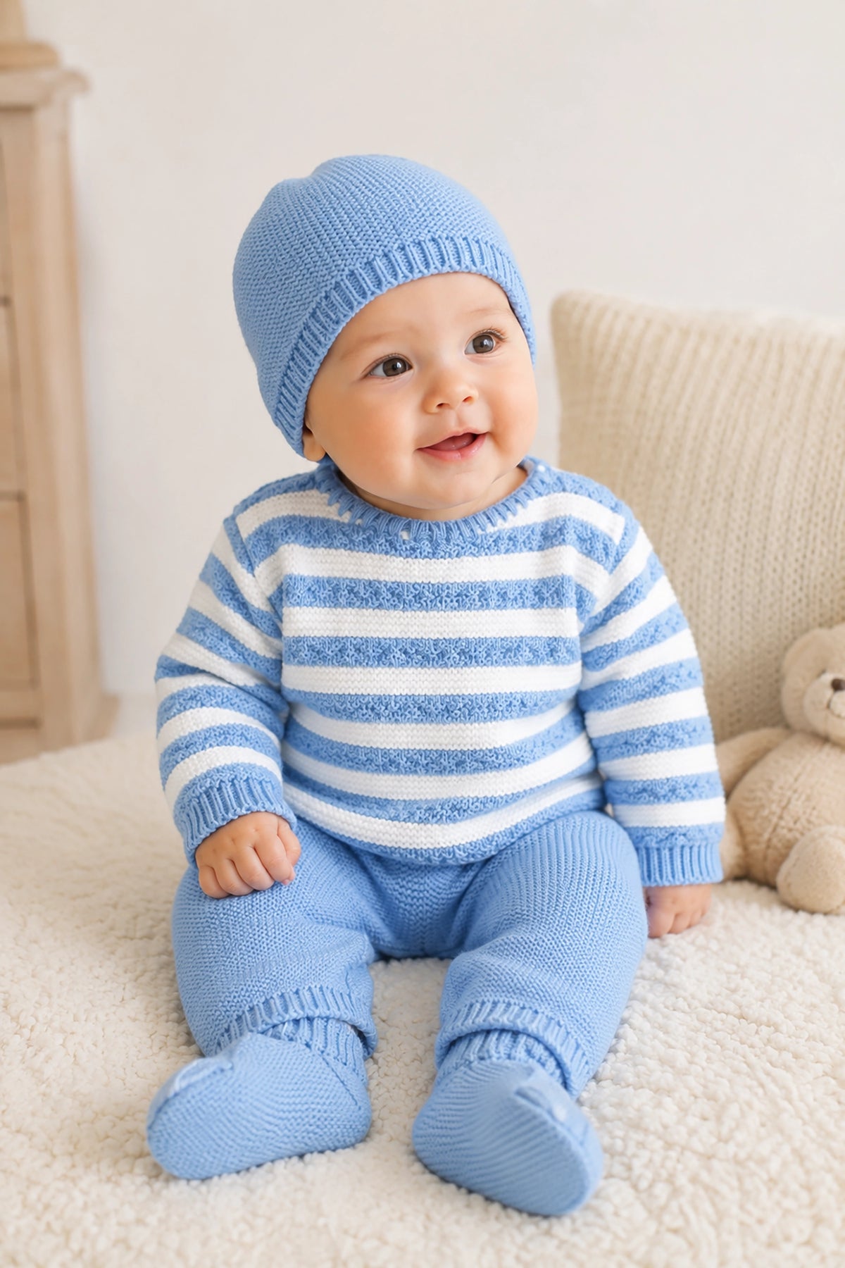 Baby wearing a blue and white striped outfit with matching hat on a light background