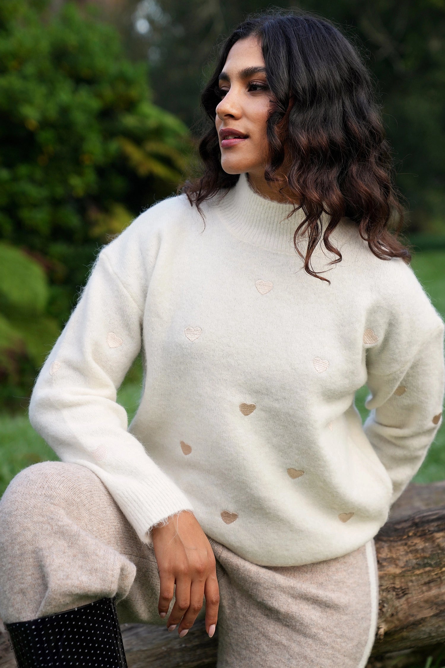 Woman wearing a cream sweater with heart patterns outdoors