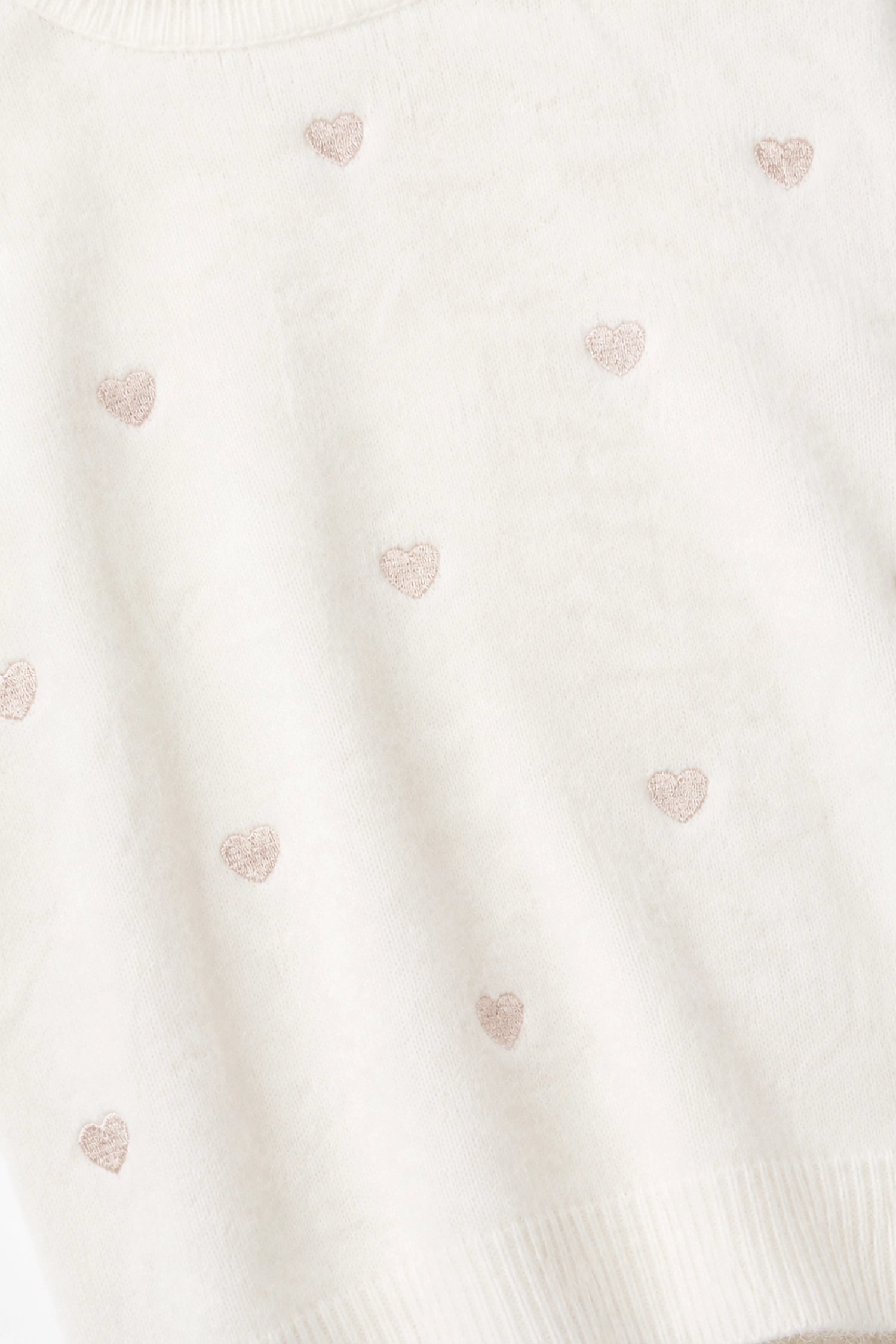 Close-up of a textured fabric with small heart patterns on a white background