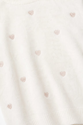 Close-up of a textured fabric with small heart patterns on a white background