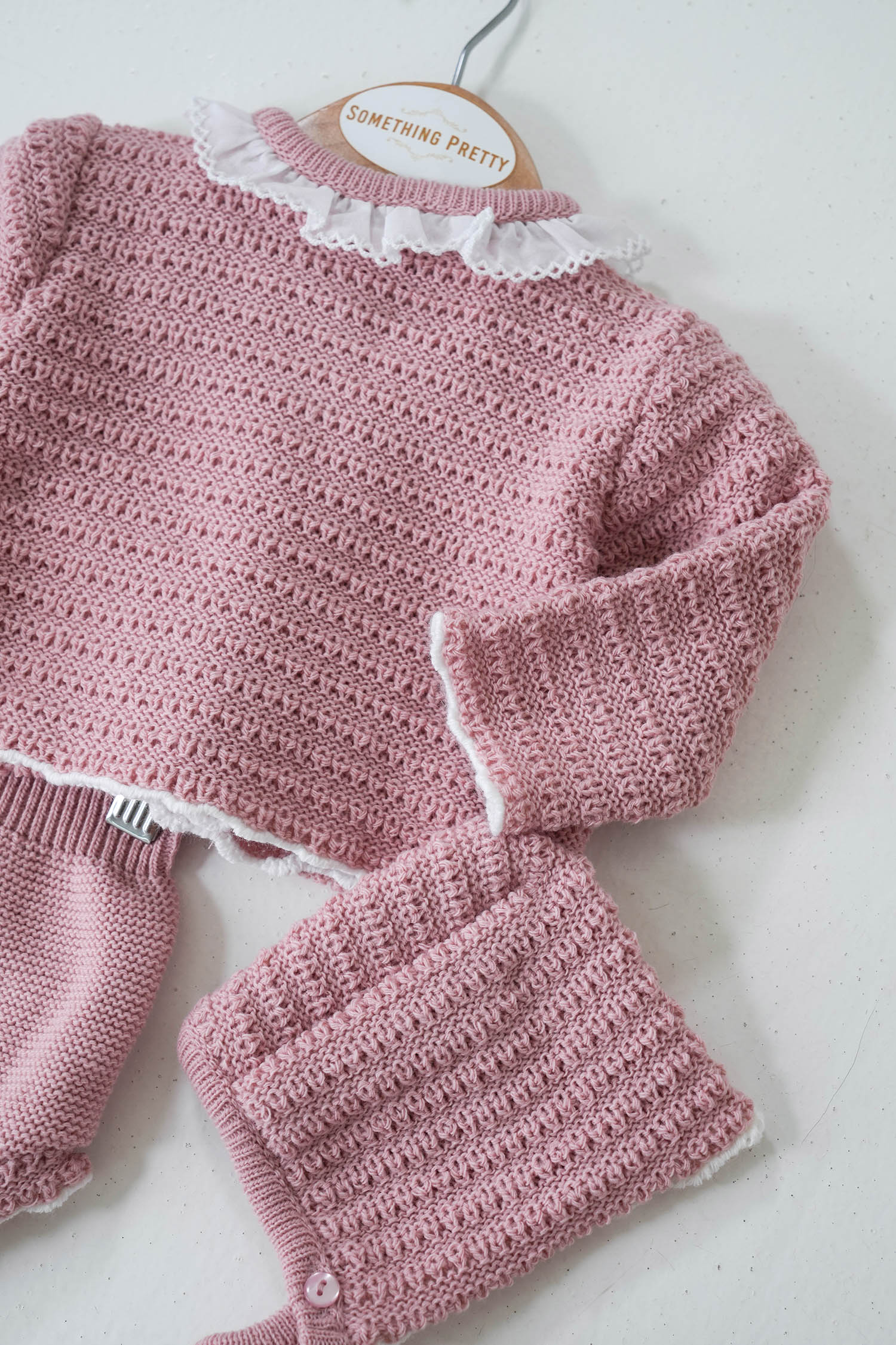 A dusty pink knit set for a girl, consisting of a long-sleeved top with a round neckline and matching pants, displayed on a mannequin.